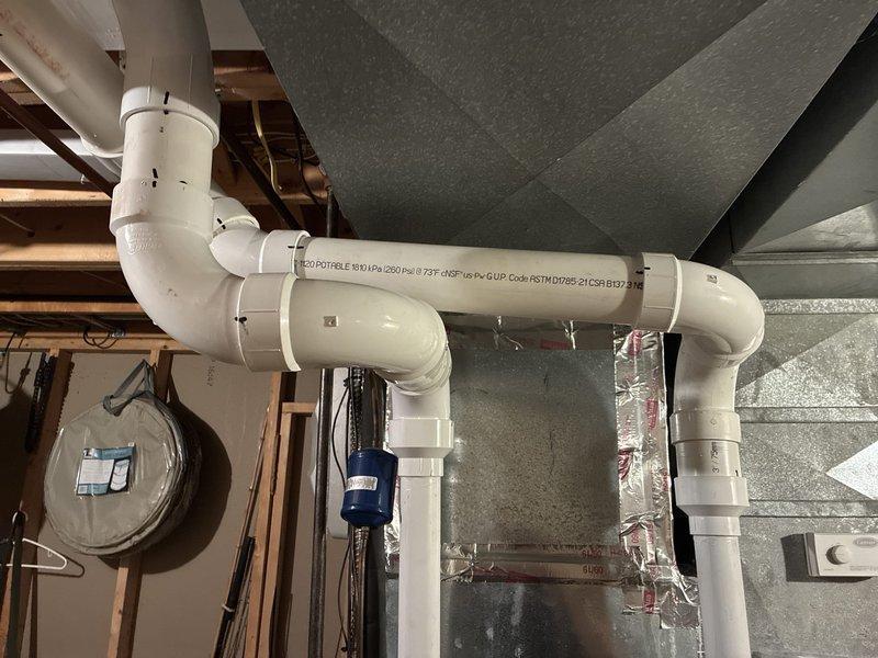 Completed installation of new 96% efficiency furnace system with integrated Carrier humidifier unit. Installation included proper venting configuration using white PVC piping with multiple elbow joints routed through basement ceiling area, connection to existing ductwork infrastructure, and mounting of humidifier to supply plenum. All components tested and verified operational upon completion.