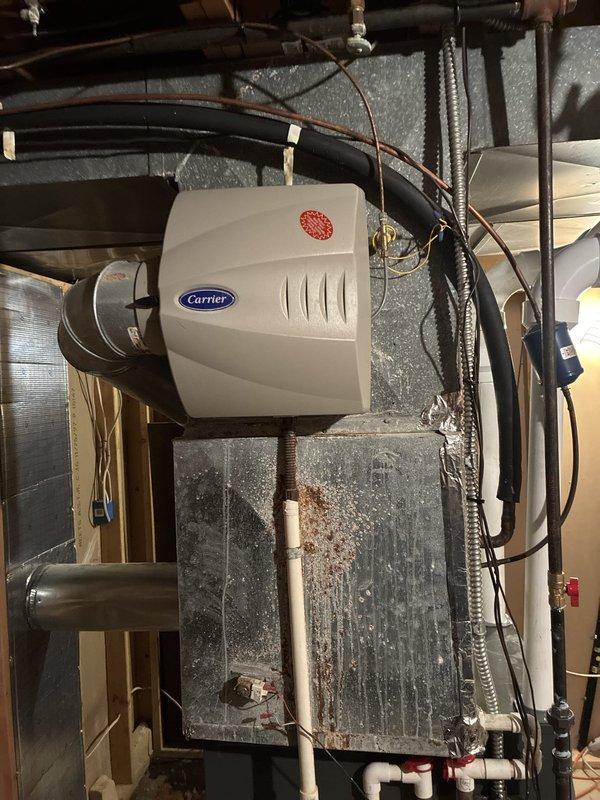 Completed installation of new 96% efficiency furnace system with integrated Carrier humidifier unit. Installation included proper venting configuration using white PVC piping with multiple elbow joints routed through basement ceiling area, connection to existing ductwork infrastructure, and mounting of humidifier to supply plenum. All components tested and verified operational upon completion.