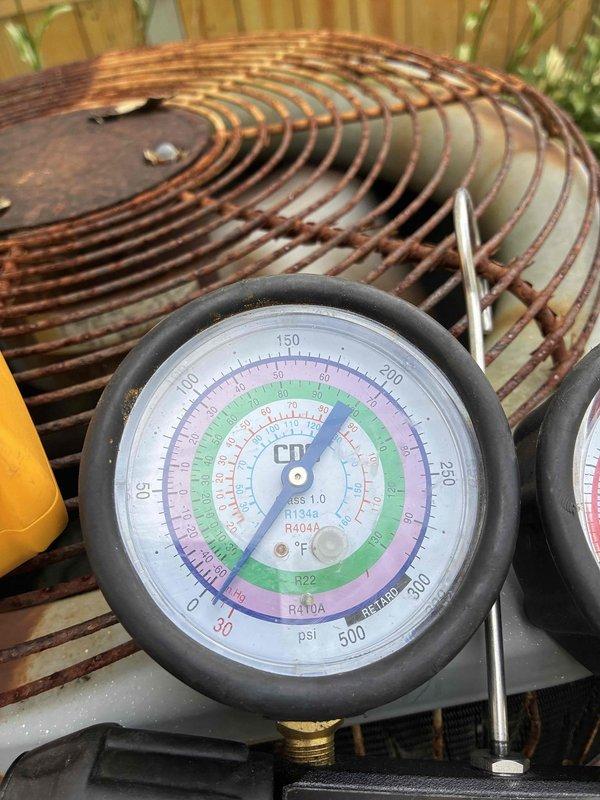 Responded to no cooling complaint on residential air conditioning system. Upon arrival, connected manifold gauges to assess refrigerant pressures and system operation. Diagnostic testing revealed abnormal pressure readings indicating potential refrigerant charge issue or system malfunction. Inspected outdoor condensing unit and noted significant rust and corrosion on fan guard, suggesting extended exposure to weather elements and potential maintenance concerns. Documented system pressures using calibrated gauges compatible with multiple refrigerant types including R-22 and R-410A. Performed visual inspection of copper coil assembly showing normal weathering patterns consistent with outdoor installation. System evaluation completed with photographic documentation of pressure readings and equipment condition for service records.