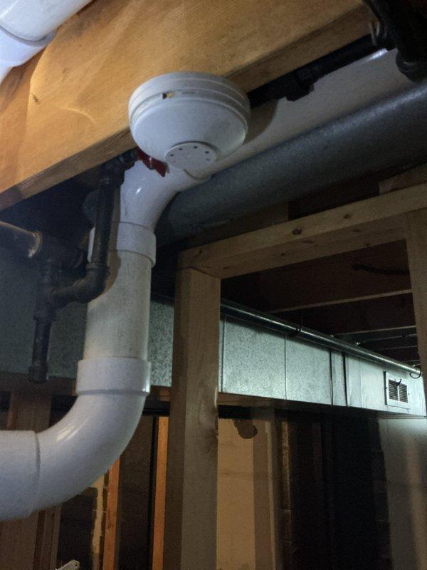 Conducted on-site assessment for gas line conversion project serving exterior fireplace. Existing black iron pipe currently runs approximately 25 feet along exterior foundation slab, requiring replacement with underground polyethylene gas line system. Evaluated current routing from interior connection point through basement area to exterior fireplace location. Documented existing black pipe configuration running exposed along building exterior where it is subject to weather exposure and potential damage. Assessed soil conditions at installation site, noting rocky, gravelly substrate with vegetation growth along foundation perimeter. Verified interior gas line connections and determined optimal transition point for new underground installation. Photographed existing plumbing infrastructure including drainage systems and structural elements to ensure proper coordination with proposed gas line burial. Recommended removal of existing exposed black iron piping and installation of approved p
