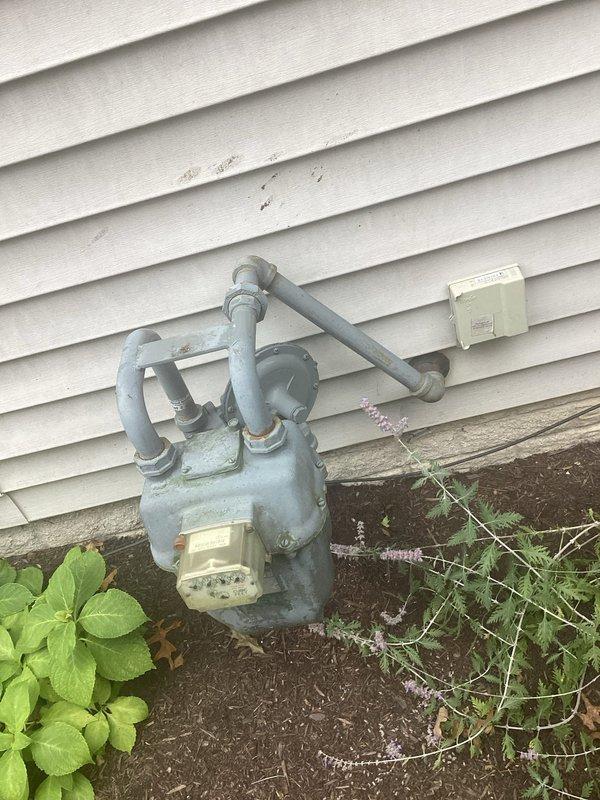# Electrical Estimate - Generator Installation Assessment

Conducted comprehensive site evaluation for backup generator installation at residential property. Assessed existing natural gas meter assembly and utility connections mounted on exterior wall to determine compatibility and capacity for generator tie-in. Documented current gas line configuration, including meter positioning, pipe routing, and available connection points for future generator fuel supply integration.

Performed basement inspection to evaluate electrical panel access and identify optimal routing path for generator transfer switch installation. Examined ceiling-mounted infrastructure including existing electrical conduit, HVAC ductwork, and plumbing systems to determine clearances and mounting locations for new electrical equipment. Assessed wooden joist structure and concrete block foundation walls for proper grounding and bonding requirements.

Photographed all relevant utility connections, gas meter assembly, an