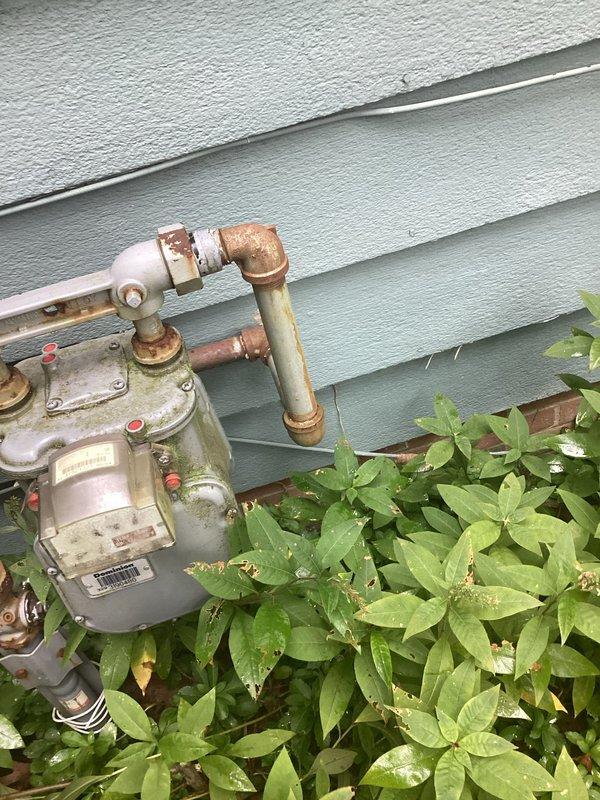 Conducted comprehensive site assessment for standby generator installation. Evaluated existing natural gas meter infrastructure and confirmed adequate gas supply capacity for generator connection. Documented current electrical service panel configuration, including available breaker positions and conduit routing for future generator transfer switch integration. Photographed gas meter piping connections showing aged copper lines with weathered patina and oxidation, noting existing infrastructure condition for connection planning. Assessed electrical panel capacity and identified optimal location for automatic transfer switch installation. Evaluated exterior mounting location relative to gas meter positioning and electrical service entry point to determine most efficient generator placement and utility connections.