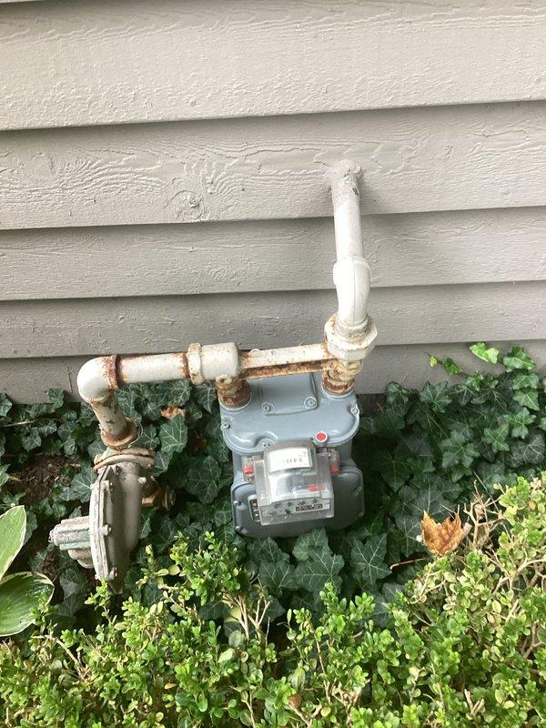 Conducted on-site electrical estimate for generator installation at residential property. Assessed existing gas meter location and foundation area to determine optimal placement and connection points for standby generator system. Documented current utility infrastructure including gas service entry point with weathered connections and available space along exterior wall with brick foundation and landscaped perimeter for equipment positioning and required clearances.