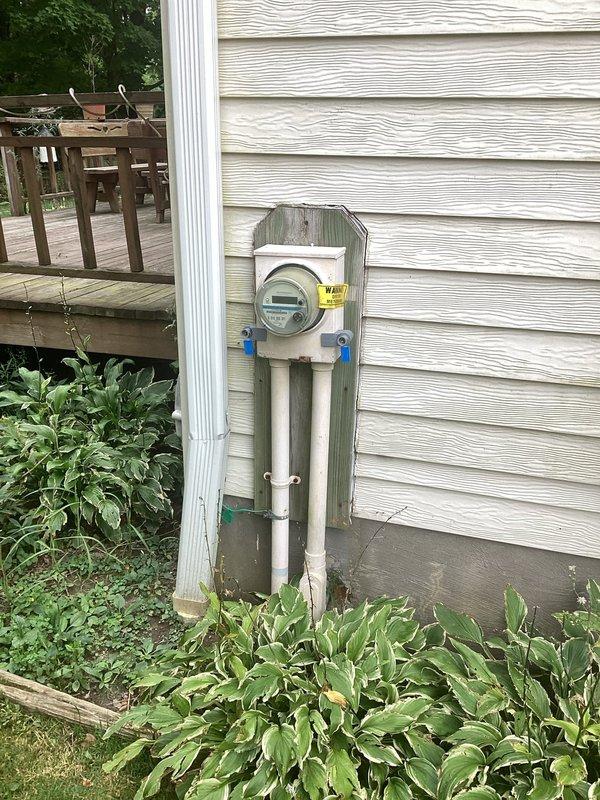Conducted electrical inspection of exterior meter installation. Documented defective meter with warning label present and verified security lock and tag were properly installed on the meter enclosure. Photographed existing weathered mounting board, PVC conduit routing, and overall service entrance configuration for records.