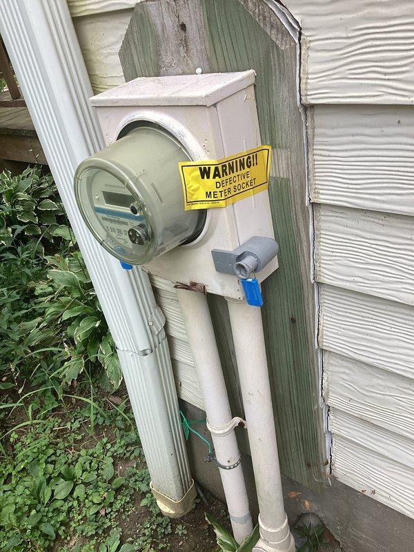 Conducted electrical inspection of exterior meter installation. Documented defective meter with warning label present and verified security lock and tag were properly installed on the meter enclosure. Photographed existing weathered mounting board, PVC conduit routing, and overall service entrance configuration for records.