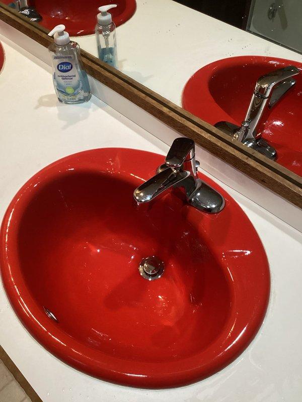 Completed installation of three Moen faucet assemblies in bathroom vanity setup, including one Moen Camerist single-handle faucet with spray feature and two Moen Chateau single-handle faucets. All units were mounted to white countertop with red ceramic basin sinks, with chrome finishes installed and drain assemblies connected. Tested all faucets for proper water flow, verified spray function operation, checked for leaks at supply connections and drain seals, and confirmed all fixtures were functioning correctly upon completion.