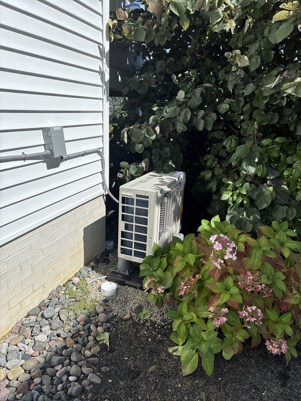 Completed mini-split system installation including outdoor condenser unit placement on equipment pad with proper clearances, line set installation through wall penetration with protective cover, and dedicated electrical circuit connection. Unit positioned on side of residence with adequate airflow access, all refrigerant lines properly insulated and secured, electrical conduit run from meter to disconnect and condensing unit. System tested and operational, balance of payment collected upon completion. Completed mini-split system installation including outdoor condenser unit placement on equipment pad with proper clearances, line set installation through wall penetration with protective cover, and dedicated electrical circuit connection. Unit positioned on side of residence with adequate airflow access, all refrigerant lines properly insulated and secured, electrical conduit run from meter to disconnect and condensing unit. System tested and operational, balance of payment collected upon completion.