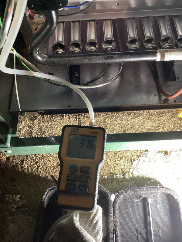 Completed scheduled heating system tune-up and maintenance inspection on boiler and hot water heater. Performed diagnostic testing with digital meter showing heat exchanger temperature at 37.6°F, inspected expansion tank, brass valve assembly, and copper piping connections throughout the mechanical room. Documented water staining and discoloration on concrete floor around equipment base to address customer's concern regarding dampness around units; recommended monitoring for potential leaks in plumbing connections or condensate drainage issues.