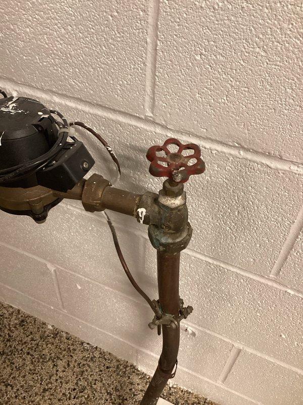 Responded to emergency no-water call at 1989-construction residence with failed original plumbing infrastructure. Inspected main water shutoff valve in basement and identified severely corroded brass valve with compromised seating and aged copper supply line showing significant oxidation. Documented existing PVC distribution piping with access point through interior wall cavity, revealing aged coupling connections. Due to emergency nature of complete water loss, prioritized immediate assessment and coordinated with customer regarding urgency of restoration timeline and available repair options for failed main shutoff assembly.