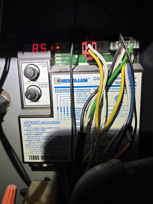 Responded to service call for Weil-McLain CGa-3 PIDN natural gas boiler that was not operating correctly after homeowner's recent property purchase. Upon arrival, performed system inspection and diagnostic evaluation of the 67,000 BTU/hr unit. Examined control board, sequence of operation module, and safety lockout indicators including damper, flame sensor, and low water cutoff (LWCO) systems. Verified electrical connections, reviewed digital display readings showing 85°F, and assessed temperature control settings on economy adjust and temperature end knobs. Documented unit specifications including 56 MBH heat output, 50 PSI maximum water pressure rating, and 260°F maximum water temperature capacity. Inspected wiring harness connections and safety control modules to identify potential operational issues preventing proper system startup. Responded to service call for Weil-McLain CGa-3 PIDN natural gas boiler that was not operating correctly after homeowner's recent property purchase. Upon arrival, performed system inspection and diagnostic evaluation of the 67,000 BTU/hr unit. Examined control board, sequence of operation module, and safety lockout indicators including damper, flame sensor, and low water cutoff (LWCO) systems. Verified electrical connections, reviewed digital display readings showing 85°F, and assessed temperature control settings on economy adjust and temperature end knobs. Documented unit specifications including 56 MBH heat output, 50 PSI maximum water pressure rating, and 260°F maximum water temperature capacity. Inspected wiring harness connections and safety control modules to identify potential operational issues preventing proper system startup.