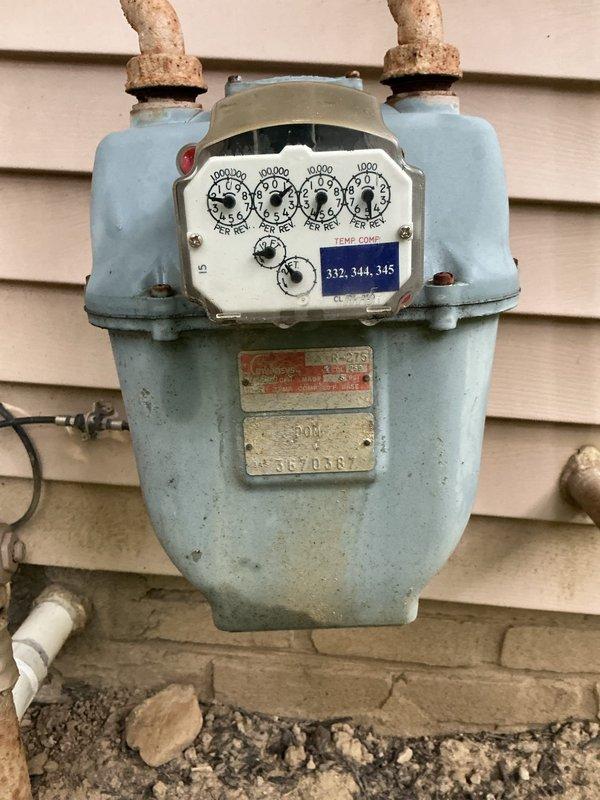 Conducted comprehensive site evaluation for standby generator installation at residential property. Assessed existing natural gas infrastructure, including aged exterior gas meter with multiple dials and corroded brass connections, and interior gas line configuration featuring copper piping, black flow control device, and red-handled shut-off valve mounted on basement utility wall. Documented current electrical panel location and utility connections to determine optimal generator placement, fuel source accessibility, and transfer switch integration requirements. Photographed all relevant infrastructure components to support equipment sizing recommendations and installation planning.