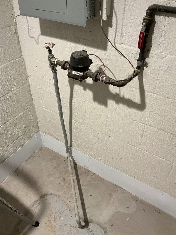 Conducted comprehensive site evaluation for standby generator installation at residential property. Assessed existing natural gas infrastructure, including aged exterior gas meter with multiple dials and corroded brass connections, and interior gas line configuration featuring copper piping, black flow control device, and red-handled shut-off valve mounted on basement utility wall. Documented current electrical panel location and utility connections to determine optimal generator placement, fuel source accessibility, and transfer switch integration requirements. Photographed all relevant infrastructure components to support equipment sizing recommendations and installation planning.