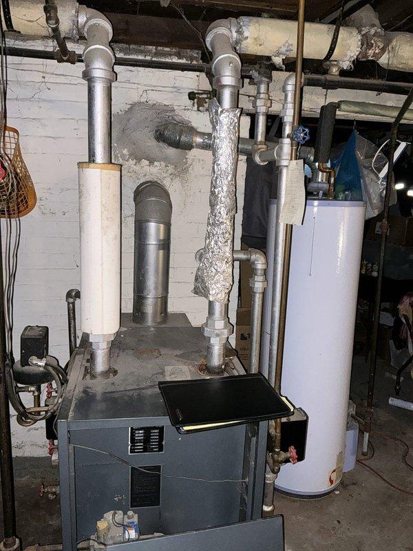 Performed on-site evaluation of 20-year-old steam boiler system located in basement mechanical room for replacement estimate. Assessed existing boiler unit, associated steam piping, insulation condition, and connected water heater to determine scope of replacement work. Documented current system configuration including deteriorated pipe insulation, copper supply lines, electrical connections, and existing mechanical infrastructure to provide comprehensive replacement recommendations.