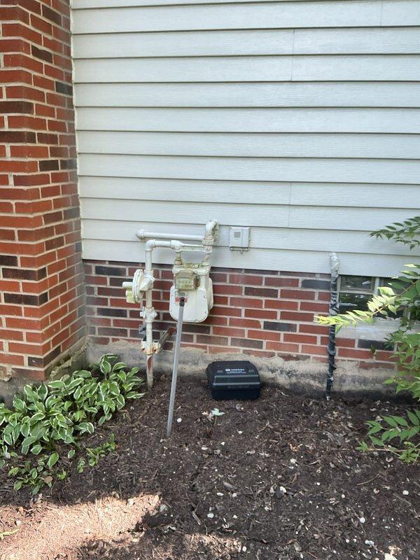 Completed on-site electrical estimate for residential standby generator installation. Assessed exterior mounting location on white vinyl siding near existing gas meter and utility infrastructure at foundation level, evaluating accessibility for generator placement, fuel line connection, and proper clearances from building structure and landscaping. Inspected basement utility room and documented existing electrical service panel location, main water service entry point, and available routing paths for electrical conduit and transfer switch installation. Photographed site conditions including exterior utility connections, foundation area, and interior basement infrastructure to support equipment sizing recommendations and installation planning.