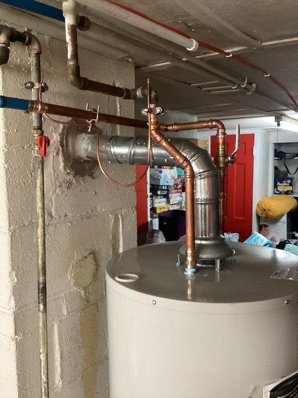 Installed a 50-gallon power vent water heater in basement utility room with all required code upgrades. The installation included proper venting through PVC exhaust system, copper supply line connections, expansion tank mounting with appropriate wall strapping, pressure relief valve installation, and gas line connection with shutoff valve. All plumbing connections were completed using copper piping with proper fittings and soldering, ensuring leak-free operation and compliance with current building codes.