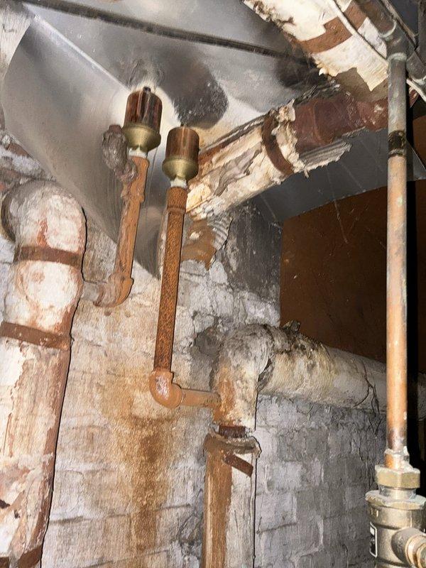 Conducted comprehensive boiler replacement estimate for mixed-use commercial property with bar and residential apartment units. Assessed existing boiler system in basement utility area showing significant aging infrastructure, including corroded copper piping, deteriorated valves, and moisture concerns on concrete flooring. Documented current mechanical room conditions with exposed plumbing configurations, presented multiple boiler replacement options suitable for the building's heating requirements, and provided pricing with applicable equipment discounts.
