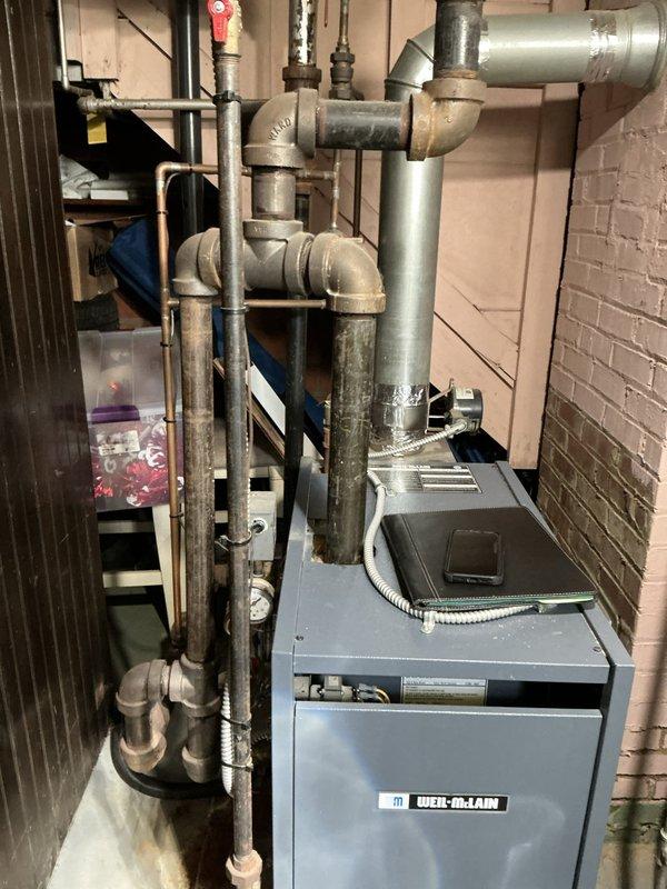 Conducted comprehensive inspection of Weil-McLain boiler system in basement following reports of visible corrosion and concerns about potential replacement needs. Assessed boiler unit of unknown age, examining all accessible components including the heat exchanger, piping connections, and control systems. Evaluated existing piping infrastructure, noting combination of older weathered piping showing signs of age and corrosion alongside newer ductwork installations. Inspected all pipe joints, connections, and valve assemblies for integrity and potential leak points. Documented condition of boiler casing, internal components where accessible, and surrounding mechanical systems. Photographed equipment and piping configuration to support estimate preparation for repair versus replacement options, providing detailed assessment of system condition and recommendations for next steps.