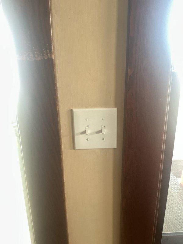 Replaced two defective light switches with new toggle switches on dual gang plate mounted to vertical beam in entryway area. Removed existing switch plate, disconnected old switches, installed new switches ensuring proper wire connections and polarity, and secured new white plastic dual toggle switch plate. Accessed attic space to replace malfunctioning light fixture. Navigated through ceiling joists, removed old fixture, installed new lighting unit with proper electrical connections, and verified all circuits functioning correctly upon completion.