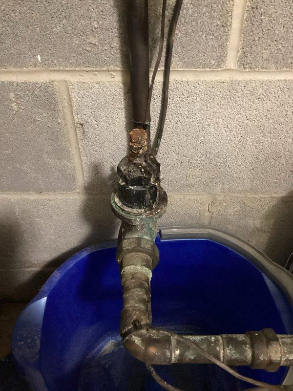 Responded to plumbing service call at vacant residential property for multiple leak issues in basement. Assessed and addressed water pressure reducing valve (PRV) leak showing significant corrosion and deterioration on curved pipe section. Inspected drain pipe leak in basement area with bucket positioned to catch water. Evaluated sump pump discharge system on exterior back left side of building, identifying cracked PVC pipe requiring repair at 90-degree elbow joint connection. Documented all affected plumbing components with photographs showing extent of corrosion on metal piping and damage to exterior drainage system. Provided assessment and repair recommendations for corroded PRV assembly, basement drain leak, and compromised sump pump discharge line to prevent future water damage. Responded to plumbing service call at vacant residential property for multiple leak issues in basement. Assessed and addressed water pressure reducing valve (PRV) leak showing significant corrosion and deterioration on curved pipe section. Inspected drain pipe leak in basement area with bucket positioned to catch water. Evaluated sump pump discharge system on exterior back left side of building, identifying cracked PVC pipe requiring repair at 90-degree elbow joint connection. Documented all affected plumbing components with photographs showing extent of corrosion on metal piping and damage to exterior drainage system. Provided assessment and repair recommendations for corroded PRV assembly, basement drain leak, and compromised sump pump discharge line to prevent future water damage.