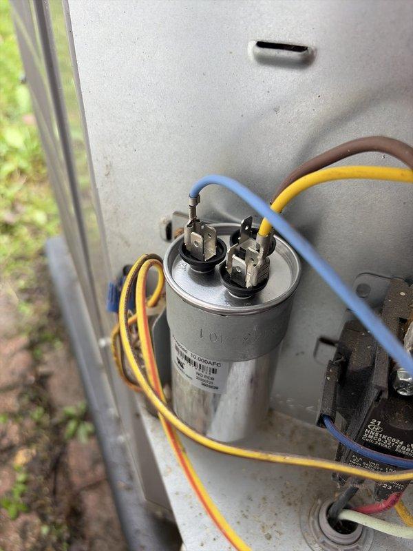 Completed comprehensive HVAC heating and cooling tune-up service on residential system. Performed electrical diagnostics using clamp meter, recording voltage readings of 100.0V and amperage of 4936mA to verify proper system operation. Inspected and tested dual-run capacitor rated at 10µF/370VAC, confirmed secure terminal connections with blue and yellow lead wires, and verified contactor functionality. All components operating within manufacturer specifications with no deficiencies noted.