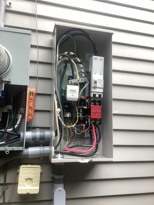 # Generator Installation Summary

Completed installation of a 22kW standby generator system under standard warranty specifications. Mounted all electrical components to exterior siding including transfer switch panels, circuit breakers, surge protection devices, and control modules with proper conduit runs and junction boxes. Established secure electrical connections with appropriate wire gauges, completed metering integration, and verified all safety disconnects and control systems are functioning correctly.

# Detailed Work Performed

Installed a complete 22kW automatic standby generator electrical system on residential exterior. Mounted dual electrical panels to building siding, containing automatic transfer switch (ATS) components and associated circuit protection devices. Installed circuit breakers, control modules with digital displays, and surge protection equipment within weather-resistant enclosures.

Ran gray PVC conduit vertically along exterior wall to house electrical feed