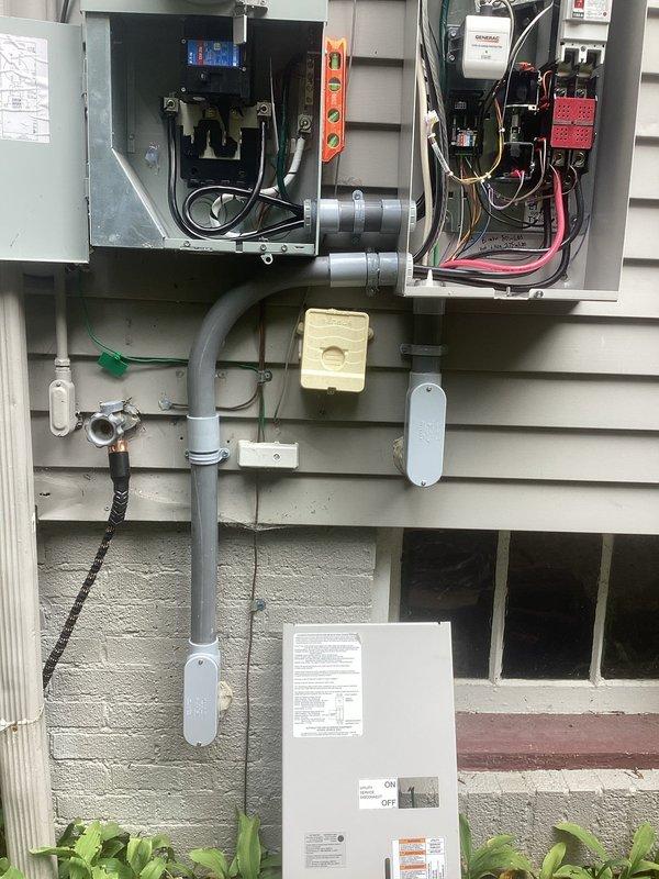 # Generator Installation Summary

Completed installation of a 22kW standby generator system under standard warranty specifications. Mounted all electrical components to exterior siding including transfer switch panels, circuit breakers, surge protection devices, and control modules with proper conduit runs and junction boxes. Established secure electrical connections with appropriate wire gauges, completed metering integration, and verified all safety disconnects and control systems are functioning correctly.

# Detailed Work Performed

Installed a complete 22kW automatic standby generator electrical system on residential exterior. Mounted dual electrical panels to building siding, containing automatic transfer switch (ATS) components and associated circuit protection devices. Installed circuit breakers, control modules with digital displays, and surge protection equipment within weather-resistant enclosures.

Ran gray PVC conduit vertically along exterior wall to house electrical feed