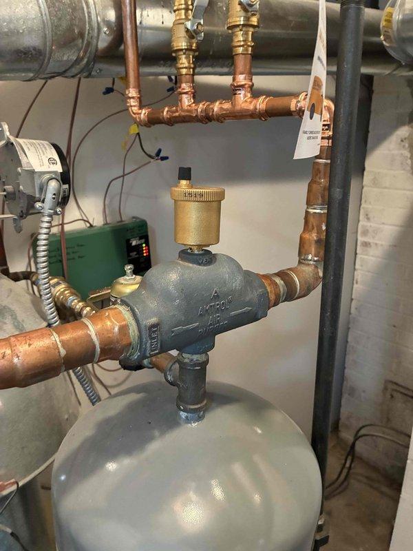 Completed installation of zone valve system with three new zone circulators for multi-zone hydronic heating system. Installed new expansion tank, automatic air eliminator, pressure-temperature relief valve, and multiple 3/4" ball valves with drain connections throughout the manifold assembly. All copper piping connections were properly fitted and secured, with electronic zone pumps mounted and wired to provide independent temperature control for separate heating zones.
