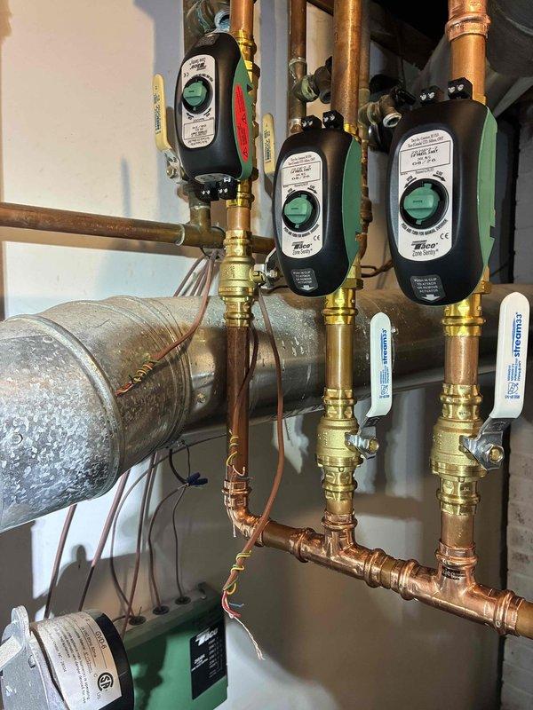 Completed installation of zone valve system with three new zone circulators for multi-zone hydronic heating system. Installed new expansion tank, automatic air eliminator, pressure-temperature relief valve, and multiple 3/4" ball valves with drain connections throughout the manifold assembly. All copper piping connections were properly fitted and secured, with electronic zone pumps mounted and wired to provide independent temperature control for separate heating zones.