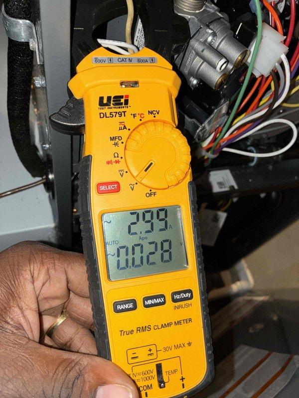 Performed comprehensive HVAC cooling system maintenance on window unit. Conducted electrical diagnostics using clamp meter, measuring amperage draw at 2.93A and voltage at 0.028V to verify proper system operation. Inspected and tested capacitor with connected yellow, purple, and red/brown wiring, confirming secure terminal connections and proper mounting bracket integrity. All electrical components showed normal operation with no signs of damage, corrosion, or unusual wear, and system is functioning within manufacturer specifications.