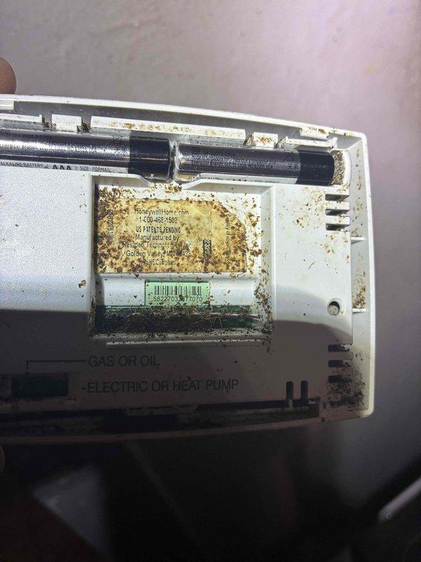 Responded to no heat call where thermostat was not communicating with furnace. Upon inspection, found wall-mounted thermostat with severe dust and debris accumulation on exterior housing and internal components. Removed thermostat cover and discovered extensive battery acid leakage and corrosion throughout battery compartment, which had compromised electrical contacts and prevented proper operation. Cleaned corroded terminals, replaced batteries, and restored communication between thermostat and heating system. Responded to no heat call where thermostat was not communicating with furnace. Upon inspection, found wall-mounted thermostat with severe dust and debris accumulation on exterior housing and internal components. Removed thermostat cover and discovered extensive battery acid leakage and corrosion throughout battery compartment, which had compromised electrical contacts and prevented proper operation. Cleaned corroded terminals, replaced batteries, and restored communication between thermostat and heating system.