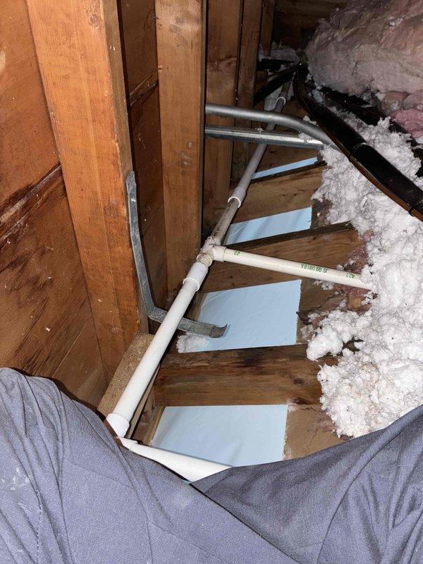 Reinstalled and rerouted PVC condensate drain line in attic space. Replaced existing drain piping with new white PVC pipe, ensuring proper pitch and secure connections throughout the run. Repositioned drain line between ceiling joists for improved drainage flow and to prevent future backup issues. Verified all pipe joints are sealed and tested system for proper operation.