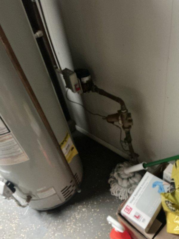 Conducted site assessment of residential electrical panel located in living area with exposed wall framing. Panel box mounted on white paneled wall shows accessible circuit breakers requiring evaluation for upgrade or repair work. Inspected utility room containing water heater with associated electrical connections and copper piping infrastructure. Documented current panel configuration and surrounding conditions. Provided quote for electrical panel work as requested.