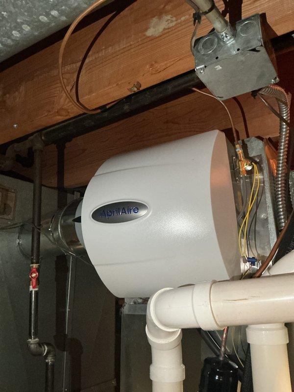 Successfully installed an AprilAire 600 whole-home humidifier integrated with the existing HVAC system. The unit was mounted to the floor joists in the utility area with proper structural support, connected to the main air handler ductwork via metallic ductwork, and plumbed with water supply lines including a shutoff valve with red handle for easy maintenance access. All electrical connections were completed with proper conduit and junction box installation, ensuring the humidification system is fully operational and ready to maintain optimal indoor humidity levels throughout the home. Successfully installed an AprilAire 600 whole-home humidifier integrated with the existing HVAC system. The unit was mounted to the floor joists in the utility area with proper structural support, connected to the main air handler ductwork via metallic ductwork, and plumbed with water supply lines including a shutoff valve with red handle for easy maintenance access. All electrical connections were completed with proper conduit and junction box installation, ensuring the humidification system is fully operational and ready to maintain optimal indoor humidity levels throughout the home.