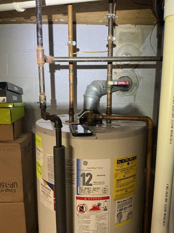 Responded to service call for reported boiler leak. Upon arrival, conducted thorough inspection of mechanical equipment and found the issue involved the water heater, not the boiler system. Documented existing installation showing 12-year warranty unit with copper piping connections, red-handled valves, and standard plumbing configuration. Photographed the equipment and surrounding plumbing connections to assess the source of the reported leak and provide visual documentation of current system condition. Responded to service call for reported boiler leak. Upon arrival, conducted thorough inspection of mechanical equipment and found the issue involved the water heater, not the boiler system. Documented existing installation showing 12-year warranty unit with copper piping connections, red-handled valves, and standard plumbing configuration. Photographed the equipment and surrounding plumbing connections to assess the source of the reported leak and provide visual documentation of current system condition.