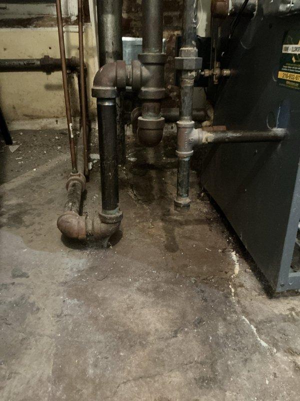 Conducted site evaluation for boiler replacement options in basement mechanical room. Assessed existing aged heating system with corroded black iron and galvanized steel piping showing significant wear and mineral deposits. Identified water line routing issue positioned above electrical panel that requires relocation to meet code compliance. Documented existing baseboard heating system infrastructure, including insulated PVC supply lines and electrical connections. Provided comprehensive replacement recommendations addressing both equipment upgrades and necessary piping modifications to ensure safe and compliant installation.