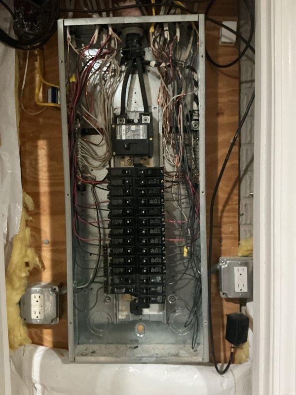 Completed comprehensive electrical inspection of residential utility space. Documented electrical panel installation showing dual-row circuit breaker configuration with main disconnect assembly and verified proper wire routing and color coding throughout the distribution system. Photographed mechanical room infrastructure including HVAC ductwork, plumbing integration, and electrical components to provide visual record of current installation status and system layout for future reference.