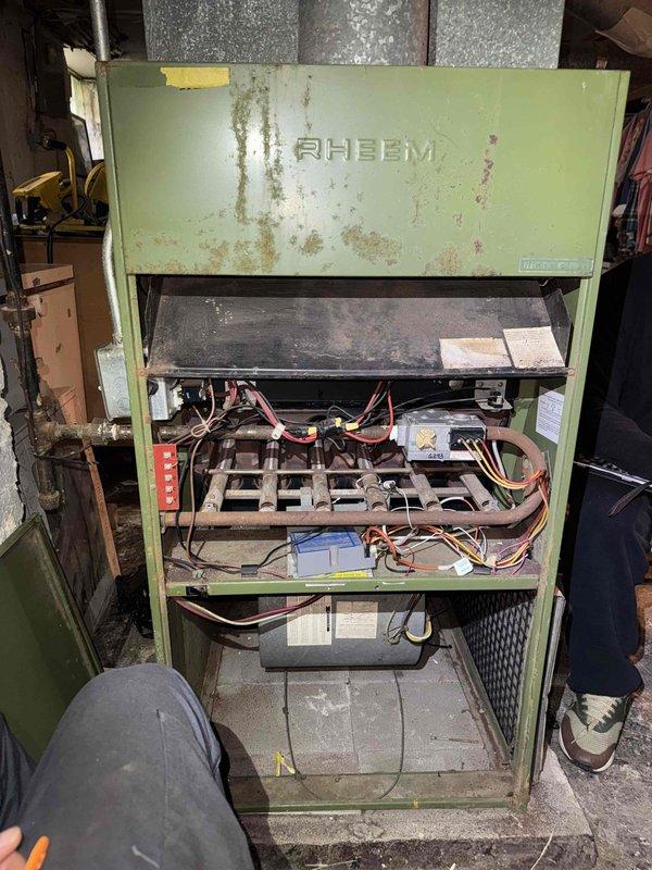 # No Heat Service Call - Rheem HVAC Unit
Responded to no heat complaint on aging Rheem HVAC system showing significant weathering and corrosion. Upon arrival, removed front access panel to inspect internal components. Unit exhibited extensive exterior rust, paint deterioration, and dirt accumulation consistent with 10+ years of operation in basement environment.
Performed thorough diagnostic inspection of internal components including blower assembly, heat exchanger, electrical connections, and copper refrigerant lines. Examined all colored wiring connections, manufacturer specification labels, and mechanical linkages. Noted advanced corrosion on copper piping with substantial oxidation and rust deposits affecting tubing integrity.
Assessed overall system condition and determined extent of wear on critical heating components. Documented unit condition through photographic evidence showing both cabinet deterioration and internal component status.
Unit restored to operational status # No Heat Service Call - Rheem HVAC Unit
Responded to no heat complaint on aging Rheem HVAC system showing significant weathering and corrosion. Upon arrival, removed front access panel to inspect internal components. Unit exhibited extensive exterior rust, paint deterioration, and dirt accumulation consistent with 10+ years of operation in basement environment.
Performed thorough diagnostic inspection of internal components including blower assembly, heat exchanger, electrical connections, and copper refrigerant lines. Examined all colored wiring connections, manufacturer specification labels, and mechanical linkages. Noted advanced corrosion on copper piping with substantial oxidation and rust deposits affecting tubing integrity.
Assessed overall system condition and determined extent of wear on critical heating components. Documented unit condition through photographic evidence showing both cabinet deterioration and internal component status.
Unit restored to operational status