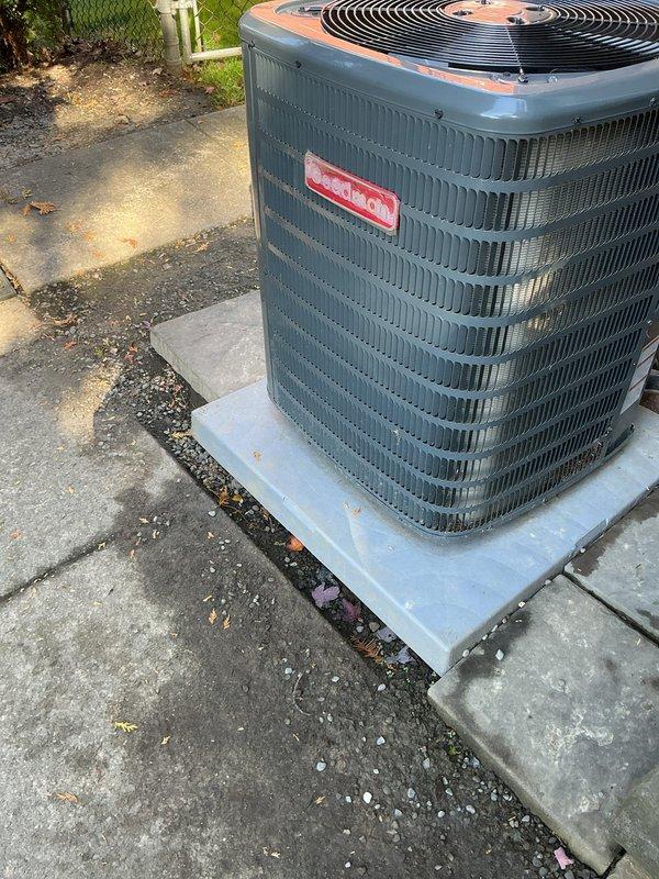Performed a cooling system tune-up on a 1-year-old Goodman outdoor condenser, inspecting the unit, condenser coil, fan assembly, electrical disconnect, and pad. The system was found operating properly, with light dirt and debris buildup noted along the lower coil section and no frost, rust, or damage present. Inspected the pad perimeter where animal digging had disturbed the base and confirmed the unit remains level and stable, with gravel present around the pad. Performed a cooling system tune-up on a 1-year-old Goodman outdoor condenser, inspecting the unit, condenser coil, fan assembly, electrical disconnect, and pad. The system was found operating properly, with light dirt and debris buildup noted along the lower coil section and no frost, rust, or damage present. Inspected the pad perimeter where animal digging had disturbed the base and confirmed the unit remains level and stable, with gravel present around the pad.