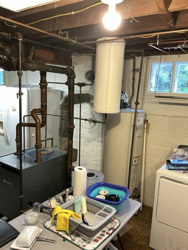 Performed an on-site evaluation of an approximately 40-year-old cast iron boiler in the basement utility area to determine replacement and upgrade options. Inspected the boiler controls, aquastat and pressure/temperature gauge, electrical disconnect, flue connection, and the aged copper and black iron distribution piping, noting heavy oxidation and tarnish throughout the system. Documented existing conditions, including clearances and venting, with photographs to support the replacement options presented to the customer. Performed an on-site evaluation of an approximately 40-year-old cast iron boiler in the basement utility area to determine replacement and upgrade options. Inspected the boiler controls, aquastat and pressure/temperature gauge, electrical disconnect, flue connection, and the aged copper and black iron distribution piping, noting heavy oxidation and tarnish throughout the system. Documented existing conditions, including clearances and venting, with photographs to support the replacement options presented to the customer.