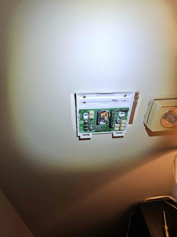 Removed the existing round dial thermostat and replaced it with a new wall-mounted thermostat. Disconnected and labeled the low-voltage control wiring (R, Y, and others) at the terminal block, then reconnected them to the new base plate and mounted it securely to the wall. Verified proper terminal connections and system operation following installation. Removed the existing round dial thermostat and replaced it with a new wall-mounted thermostat. Disconnected and labeled the low-voltage control wiring (R, Y, and others) at the terminal block, then reconnected them to the new base plate and mounted it securely to the wall. Verified proper terminal connections and system operation following installation.