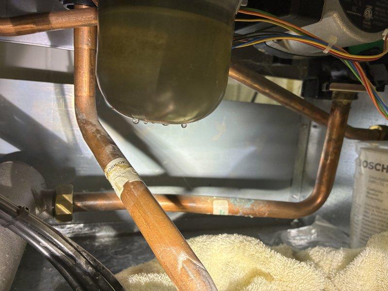 Responded to callback for leaking boiler that was previously serviced. Inspection revealed condensate drain issue caused by pinched wire between gasket and housing. Disassembled unit, removed wire, verified no damage to components, then reassembled system. Ran unit through test cycle to confirm condensate trap filled properly with no further leakage.