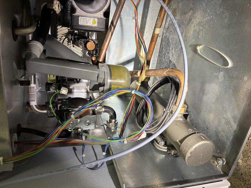 Responded to callback for leaking boiler that was previously serviced. Inspection revealed condensate drain issue caused by pinched wire between gasket and housing. Disassembled unit, removed wire, verified no damage to components, then reassembled system. Ran unit through test cycle to confirm condensate trap filled properly with no further leakage.