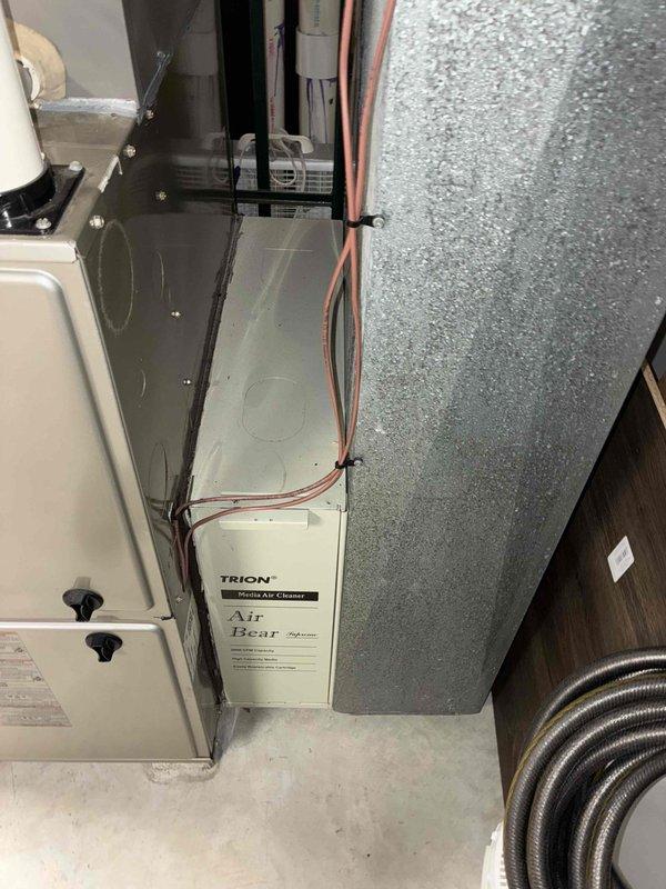 Responded to a service call for a non-functional Lennox humidifier at a new customer residence. During inspection, observed the complete HVAC system which included a beige furnace/air handler unit with a TRION "Air Bear" media air cleaner. System also featured proper drainage with PVC pipes and appropriate copper line connections. Diagnosed humidifier issue and restored functionality to improve indoor air quality.