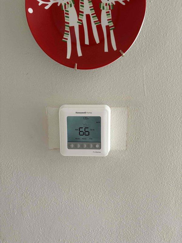 Installed new Honeywell T6 digital thermostat in customer residence, replacing previous unit. Confirmed proper connection to existing Goodman furnace system with verification of heating function (current reading 66°F, set point 70°F). System operating normally with all ductwork connections intact.