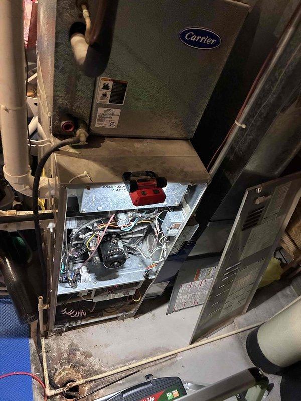 Responded to emergency no-heat call for Carrier furnace over 10 years old. Diagnostic inspection revealed failed heat exchanger and failing inducer/exhaust motor, with customer utilizing temporary box fan solution prior to arrival. Presented equipment replacement options due to age of unit and extent of critical component failures.