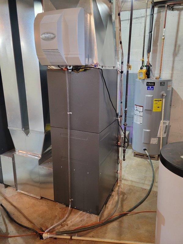 Successfully completed warranty replacement of Daikin DR96TN0804CnS furnace (S#: 2502190247) in basement utility room. Installed two humidifier units with proper connections to existing ductwork and water lines. All components tested and functioning correctly with thermostat showing proper temperature readings.