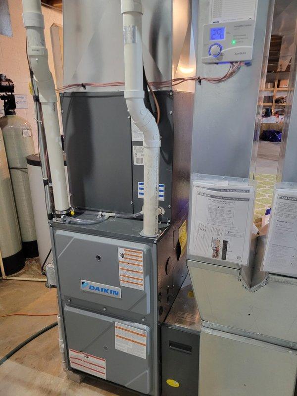 Successfully completed warranty replacement of Daikin DR96TN0804CnS furnace (S#: 2502190247) in basement utility room. Installed two humidifier units with proper connections to existing ductwork and water lines. All components tested and functioning correctly with thermostat showing proper temperature readings.