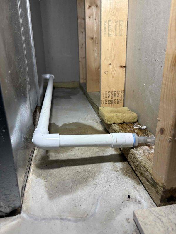 Resolved drainage issue by correcting improper PVC pipe installation in unfinished space. Repaired 90-degree elbow joint connection and addressed moisture concerns around floor penetration. Photos taken to document completed repairs for Ian's review.
