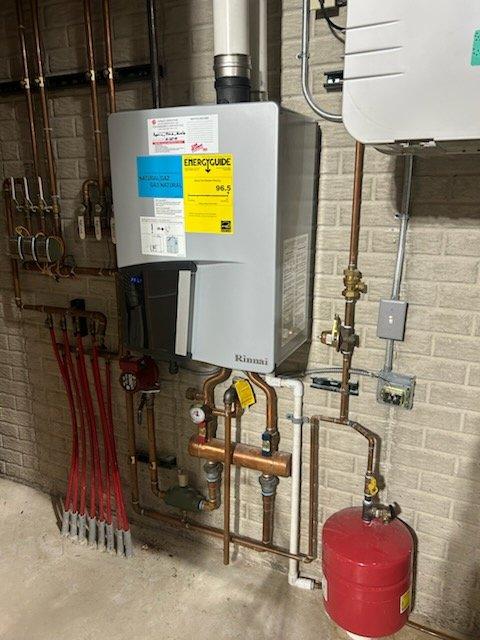 Responded to service call for Rinnai on-demand water heater/boiler system with no pressure to basement in-floor heating. Diagnostic revealed clogged flow sensor and air trapped in the heating loops. Performed system maintenance by flushing flow sensor and bleeding air from lines to restore proper operation.
