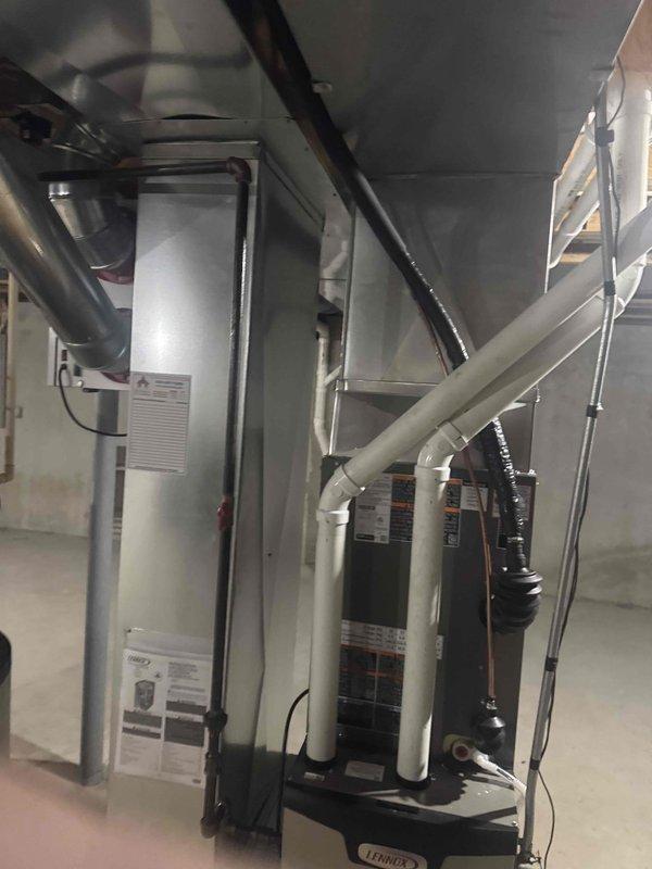 Completed installation of a 2.5 Ton Lennox EL15KC1 air conditioning system. Outdoor condenser unit was properly placed on concrete pad with electrical connections secured to exterior wall. Indoor components were installed in the basement mechanical room, including proper ductwork and PVC drainage configuration. Job was fully completed and documented with verification photos.